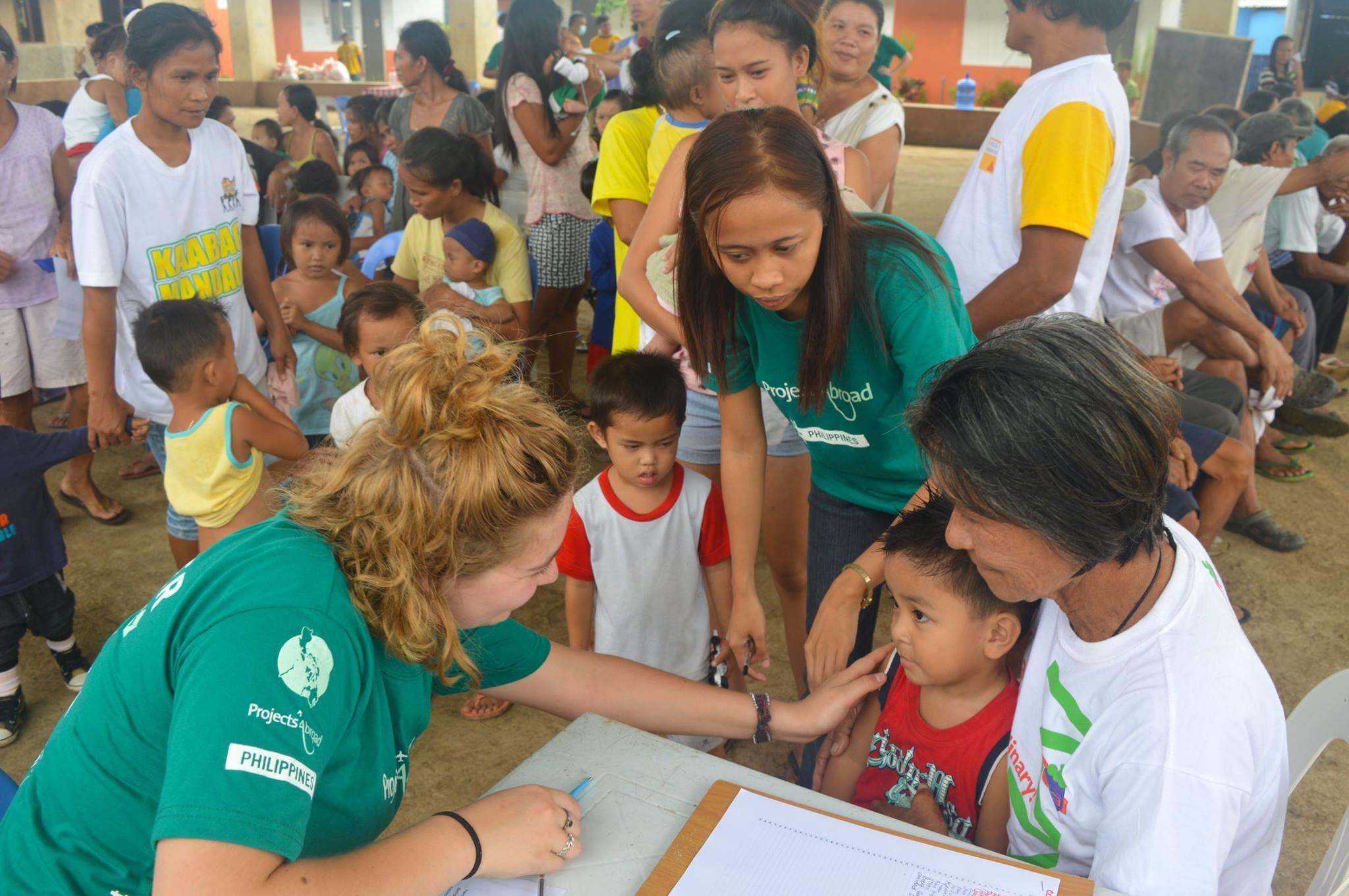 A Public Health intern talks with a young boy and his mother during a medical outreach in the Philippines. Public Health intern talking to her patient during a community outreach.